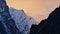 Craggy mountain range with ice-capped mountains in the Himalayas with orange cloudy sky at sunset near village Thame, Nepal.