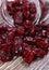 Cranberries spilling out of glass jar on wooden table