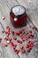Cranberry jam in glass jars. Cranberries are scattered nearby. On wooden boards with a beautiful texture
