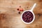 Cranberry sauce in ceramic saucepan with berries on wooden table top view