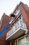 Crane boom elevator car window house brick high wash change repair help blue balcony upstairs