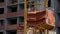 Crane and building construction site against blue sky. heavy load hanging on the hook of a crane on the construction of