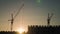 Crane and building construction site at sunset. Silhouette workers on a background of the sky.