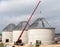 Crane on construction site. Large reinforced concrete tanks with metal roof construction