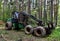 Crane forwarder machine at during clearing of a plantation. Wheeled harvester transports raw timber from the felling site out to a