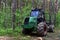 Crane forwarder machine at during clearing of a plantation. Wheeled harvester transports raw timber from the felling site out to a