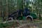 Crane forwarder machines at during clearing of a plantation. Wheeled harvester transports raw timber from the felling site out to