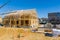 The crane holds wood truss beams as it installs construction framework rafters to the roof of an unfinished wooden house