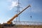 A crane installs a high voltage power line in an industrial suburb