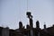 Crane lifting a concrete bucket on sunset background. Silhouettes of builders pouring cement mix for formworks at a construction