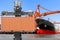 Crane lifting up container to commercial delivery cargo container truck and container ship being unloaded at the harbor