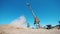 A crane moves crushed stones in a metal bucket.