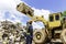 Crane operator. The engineer is controlling the loader to get the iron to recycle. Worker standing in metal landfill outdoors