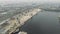 A crane picks crushed stones and sand from a barge while working at port. Industrial city with smog.