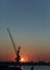 Crane on a pier silhouetted against the sunset in the harbor
