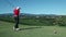 Crane shot of a woman golfer that hits a white golf ball with a golf club and
