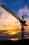 Crane silhouetted against the sunset with orange clouds