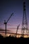 Cranes, Power Lines and Industrial Factories Silhouetted Against the Sunset