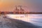 Cranes at sunset with sandy beach and reflections in the foreground at  Larnaca port, Cyprus island