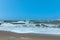 Crashing wave on a wooden groyne breakwater under a beautiful blue sky