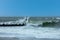 Crashing wave on a wooden groyne breakwater under a beautiful blue sky