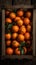 a crate filled with lots of oranges with green leaves on top of it and a wooden box behind it with leaves on top of it