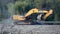 Crawler Excavator Rides on the Dirt Road on the Shore of the River Bay