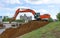 A crawler excavator working in the city on a construction site on the river bank.