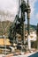 Crawler tractor with a drilling rig works behind a fence against the backdrop of a house