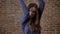 Crazy brown hair girl is showing like sign, rock sign, shaking hands, communication concept, brick background