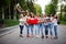 Crazy company of bridesmaids holding bride in red dress in the park at bachelorette party