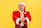 Crazy elderly man with gray beard in santa claus costume holding out sugary ice cream, looking with funny expression, showing
