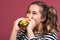 Crazy funny cool girl in striped t-shirt eating hamburger with apetite
