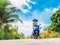 Crazy funny woman with flying hair riding a motorbike on a blue sky and green tropics background. Young girl with dark