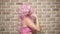 Crazy girl with pink curly hair demonstrates her biceps against a brick wall. copy space. concept of humor, adventures