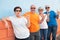 Crazy group of four senior people in friendship standing against an orange and blue wall smiling and gesturing. Cheerful and funny