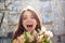 Crazy and happy young girl looking at the camera with happiness and emotions in her eyes holding a big bouquet of