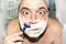 Crazy and insane man shaves in the bathroom, wide-angle photo