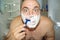 Crazy and insane man shaves in the bathroom, wide-angle photo