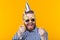 Crazy joyful cheerful young man in a cap and glasses on a yellow background. The concept of a successful party and