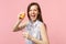 Crazy laughing young woman in summer clothes hold half of fresh ripe orange fruit, glass cup  on pink pastel