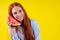 Crazy redhaired ginger woman with watermelon imagine that she talking by phone in yellow background studio wall