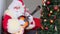 Crazy santa claus with white beard holding a guitar, playing and singing, christmas concept, waiting for gifts, new year