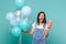 Crazy screaming young woman blinking, holding plastic cup of cola or soda celebrating with colorful air balloons