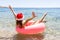 Crazy swimming with inflatable donut and christmas hat on the beach in summer sunny day