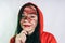 Crazy woman posing in a red hoodie with a painted face. Bizarre portrait with painted face