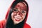 Crazy woman posing in a red hoodie with a painted face. Bizarre portrait with painted face