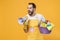 Crazy young man househusband in apron rubber gloves hold basin with detergent bottles washing cleansers doing housework