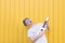 Crazy young man plays ukulele on a yellow background. Expressive musician playing guitar. Musical concept
