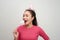 Crazy young woman in birthday hat biting round lollipop celebrating on white background